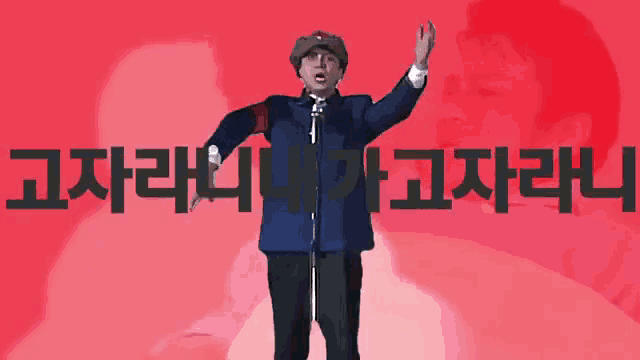 a man stands in front of a microphone in front of a red background with chinese writing on it
