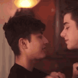 two young men are looking at each other and touching their noses