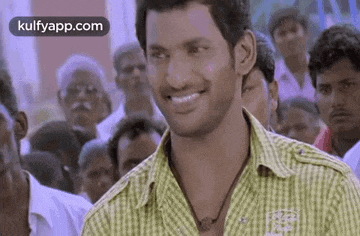a man in a green shirt is smiling in front of a crowd of people .