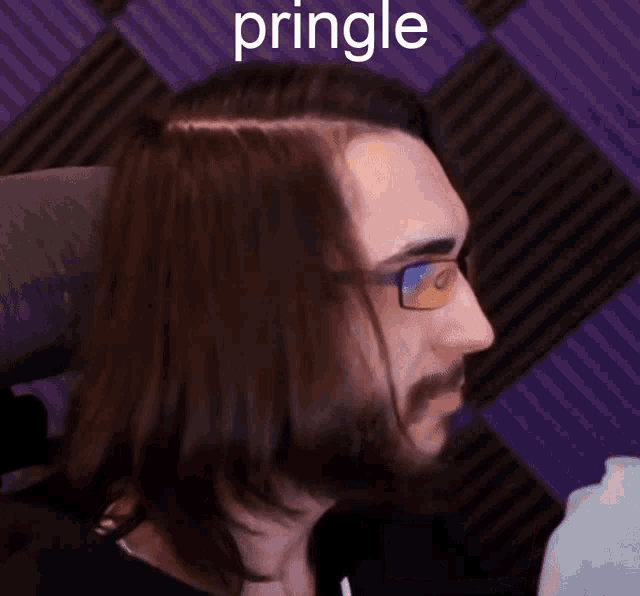 a man with long hair and glasses is eating pringles