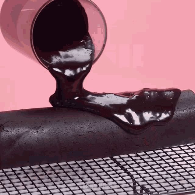a cup of chocolate is being poured onto a cake