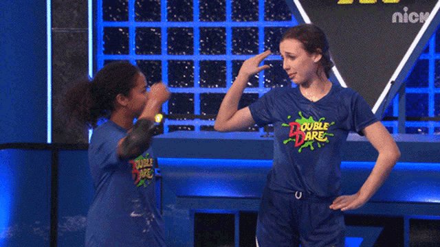 two girls wearing blue double dare shirts are giving each other a high five
