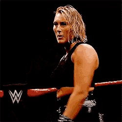 a woman is standing in a wrestling ring wearing a choker and a black top .