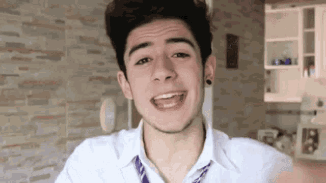 a young man wearing a white shirt and purple tie is smiling .