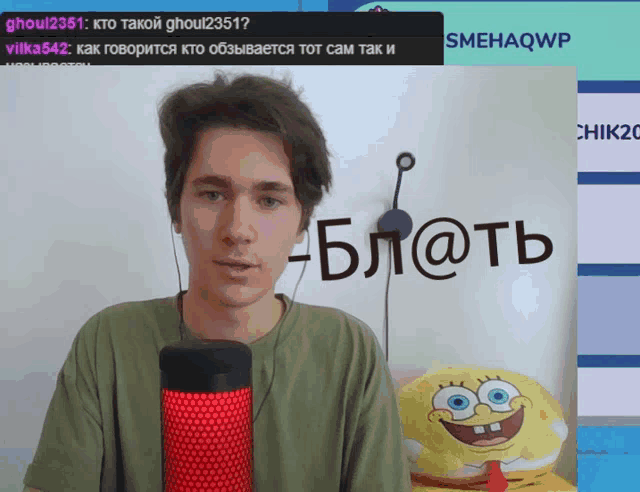 a man stands in front of a microphone with a spongebob pillow in the background