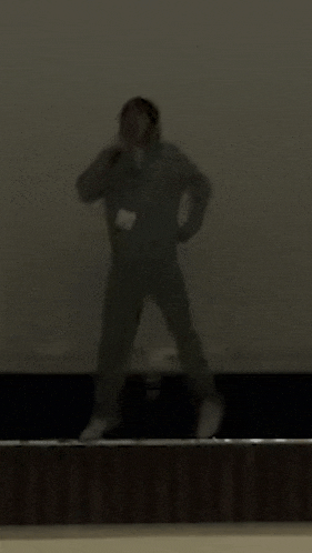 a person is standing on a stage holding a microphone in a dark room .