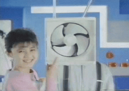 a little girl is holding a fan in front of her face and smiling .