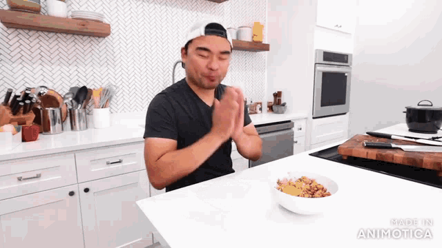 a man is clapping in a kitchen with a bowl of food in the foreground