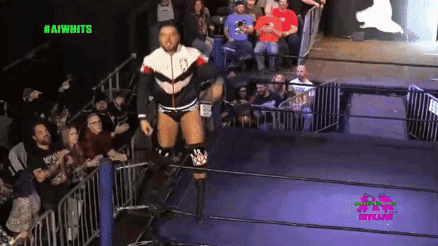 a man in a wrestling ring with #aiwhits in green