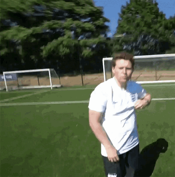 a man stands on a soccer field wearing a white shirt that says england