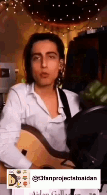 a man in a white shirt is playing a guitar and singing into a microphone .