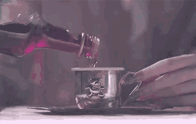 a person is pouring liquid into a cup on a saucer .