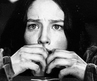 a woman covering her mouth with her hands while looking at the camera