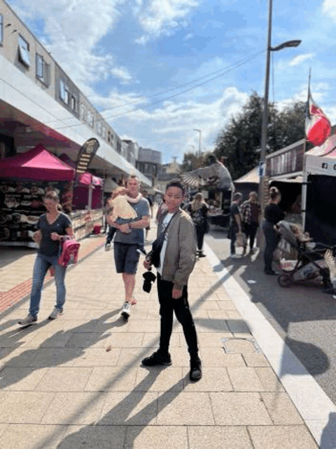 a man is standing on a sidewalk holding a baby and a bird .