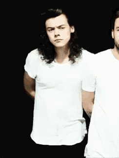 two men in white shirts are standing next to each other in a dark room .