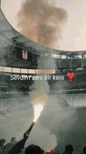 a stadium with smoke coming out of the stands and the words sevdim seni bir kere
