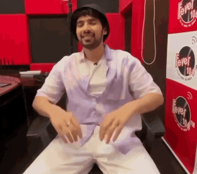 a man is sitting in a chair in front of a sign that says fever 104.5
