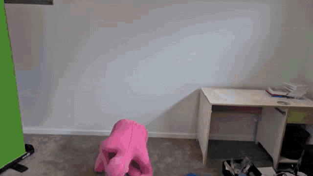 a pink stuffed animal sits in front of a desk in an empty room