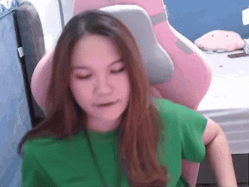 a girl in a green shirt is sitting in a pink chair .