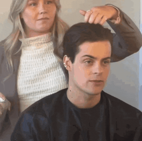 a woman is cutting a man 's hair with a comb .