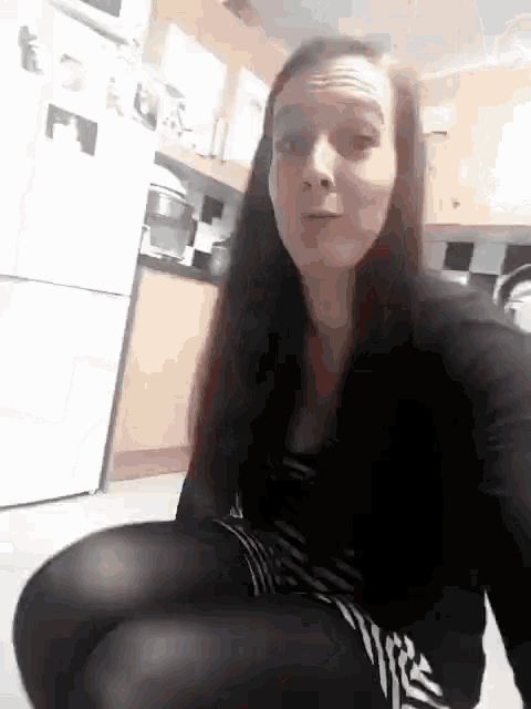 a woman is sitting on the floor in a kitchen with her legs crossed