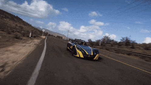 a blue and yellow sports car driving down a desert road