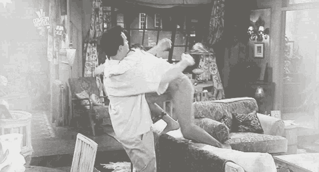 a man is holding a woman in his arms while sitting on a couch in a living room .