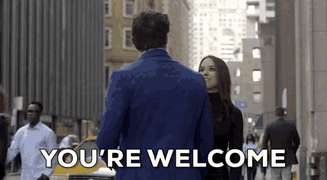 a man in a blue suit is walking down a street with a woman and says you 're welcome .