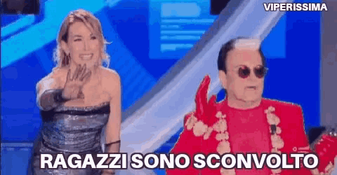 a woman in a silver dress is standing next to a man in a red suit and sunglasses ..