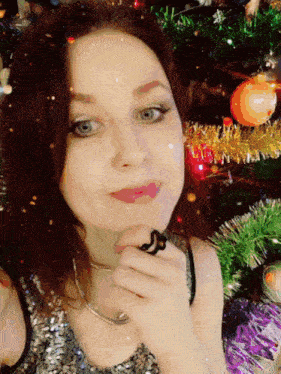 a woman in front of a christmas tree with decorations