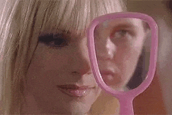 a woman is looking at her face in a pink mirror .