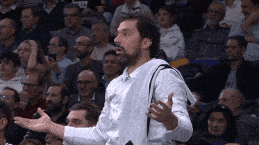 a man in a white shirt stands in front of a crowd with his hands outstretched