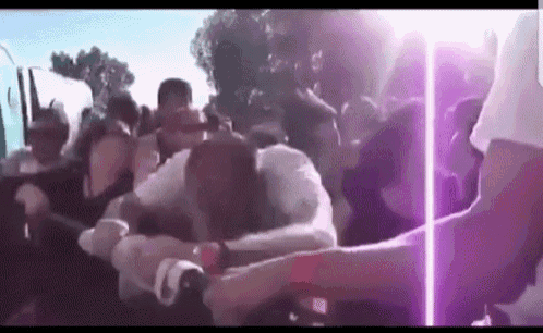 a man is holding a woman in a crowd of people at a music festival .
