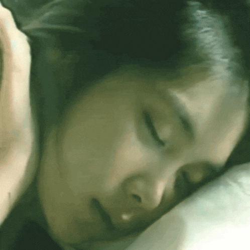 a close up of a woman sleeping on a bed