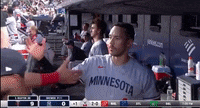 a man in a minnesota shirt shakes hands with another man in a dugout