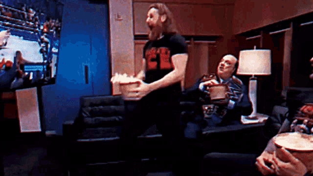 a man holding a bucket of popcorn is wearing a shirt that says ' a ' on it