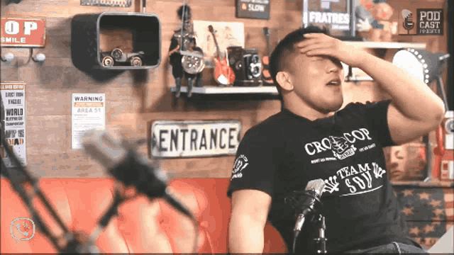 a man wearing a black shirt that says cro-cop covering his face