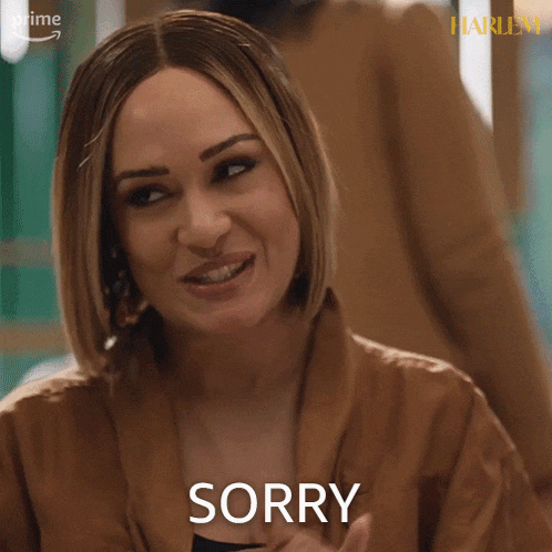 a woman in a brown jacket is making a sorry face