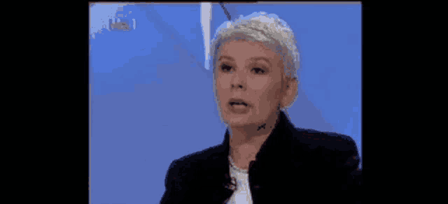a woman in a black jacket is talking on a tv show