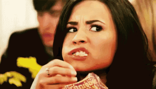 a woman is eating a bag of doritos while making a funny face .