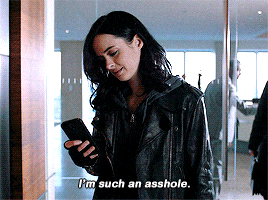 a woman in a leather jacket is holding a cell phone and saying i 'm such an asshole