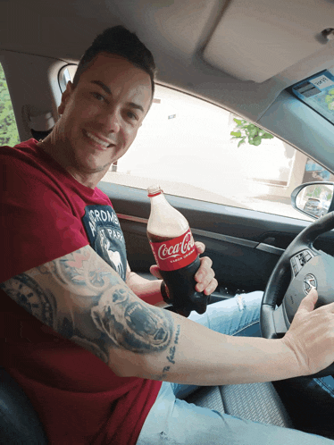 a man in a red shirt is holding a coca cola bottle