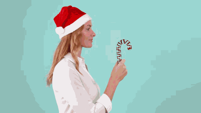 a woman in a santa hat holds a candy cane