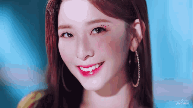 a close up of a woman 's face with a blue background and the words gifnowsn on the bottom
