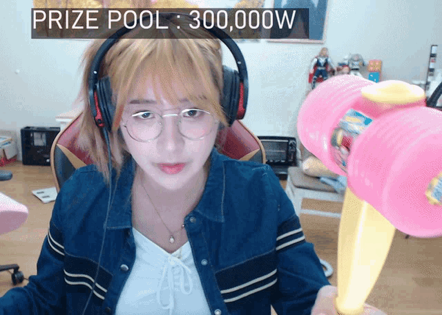 a woman wearing headphones holds a pink hammer in front of a sign that says prize pool