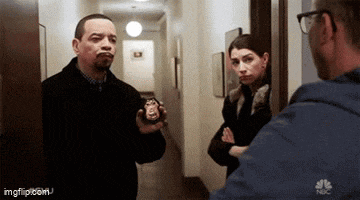 a man is holding a police badge in a hallway while talking to a woman .