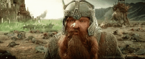 a bearded man wearing a helmet is standing in a field with a bunch of dead people .
