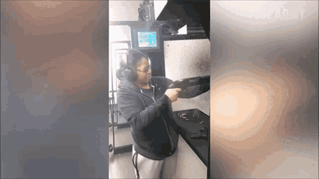 a woman wearing headphones is holding a gun at a gun range .