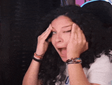 a woman with curly hair is covering her face with her hands and making a funny face