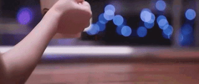 a person is holding a cup of coffee in their hand in front of a laptop .